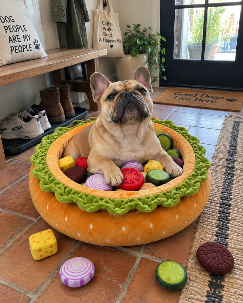 A French Bulldog sitting upright in the Burger Burrow by the front door, paws over the bun rim