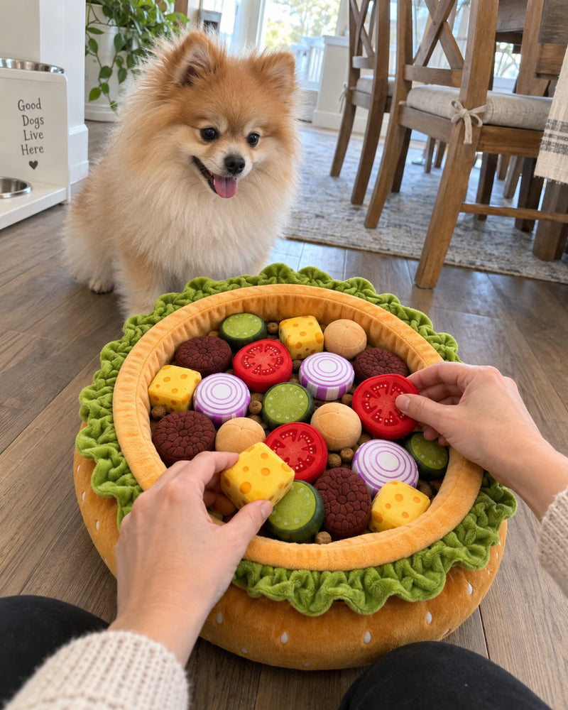 Hands arranging plush tomato and cheese pieces in the Burger Burrow while a Pomeranian waits behind it